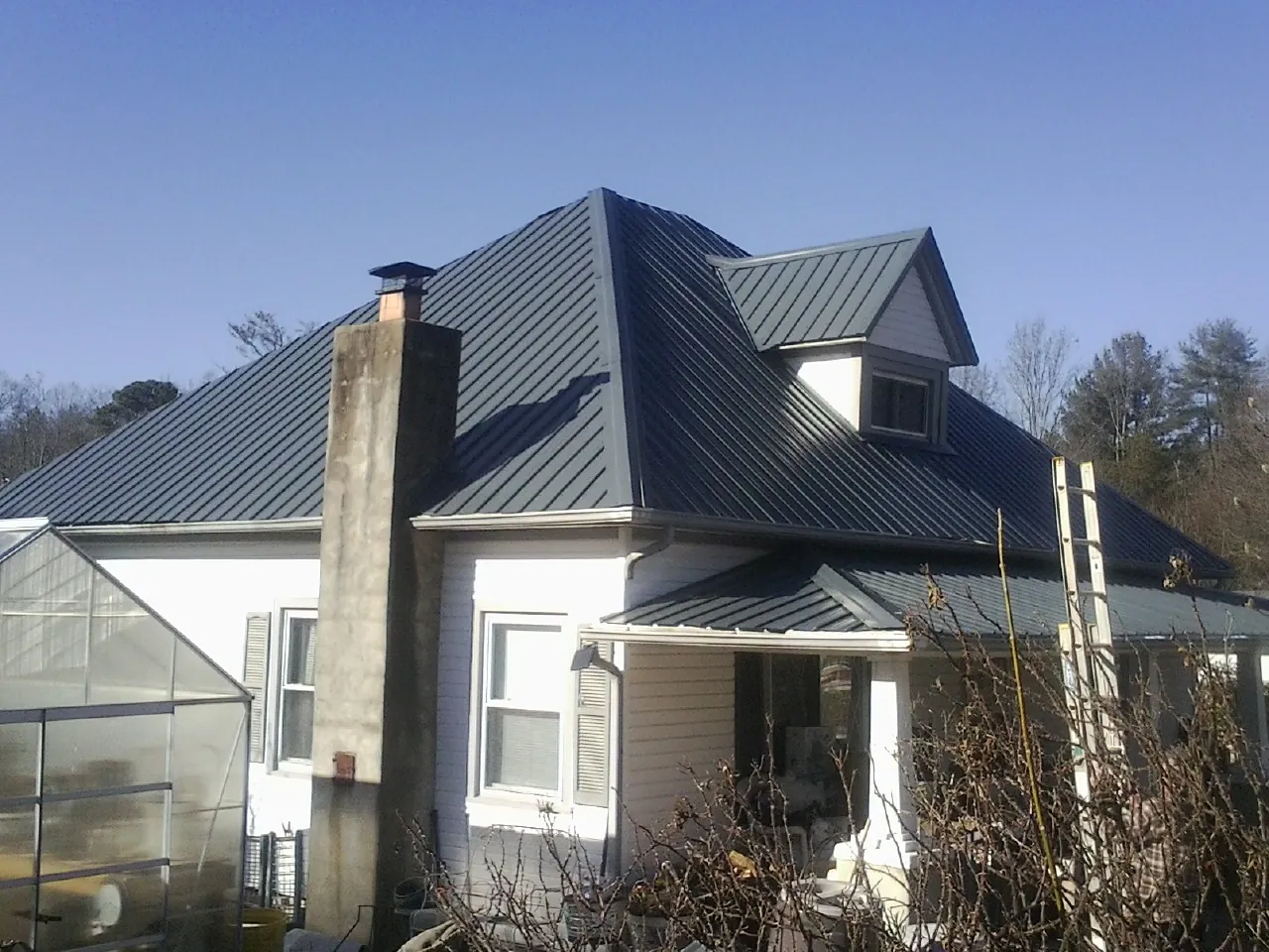 Dark blue standing seam metal roof on a white farmhouse with dormer — Slate & Tile Roof Repair by Roofing Brothers in Barre